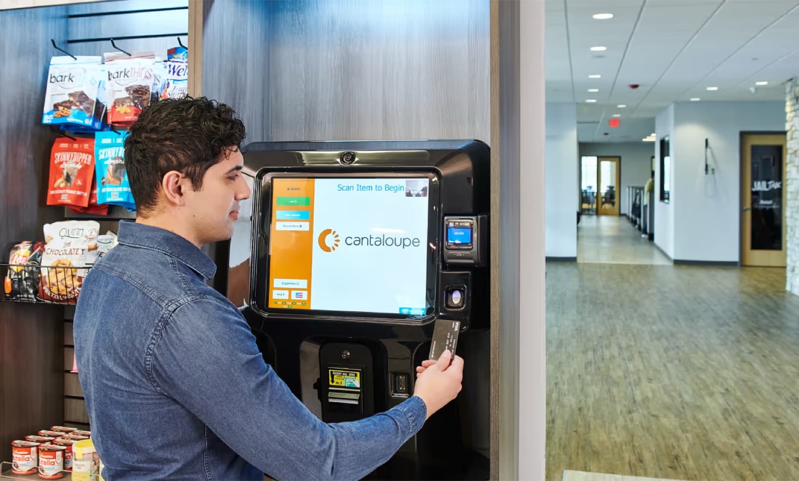 A vending machine and payment kiosk placed in a busy office corridor
